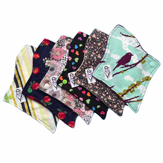 A set of six assorted tapered panty liners with various colorful patterns, against a white background. The Pads are curved at the top and tapered at the bottom.