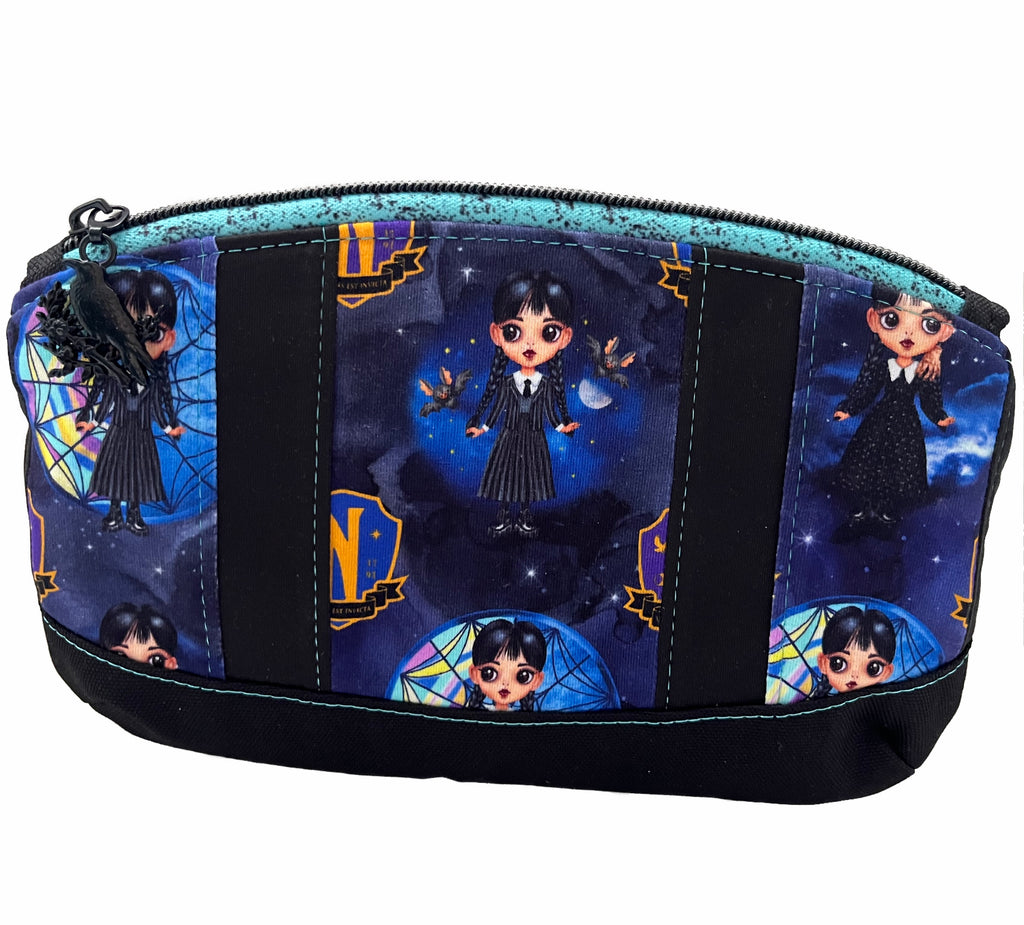 A zippered pouch against a white background. Pouch has stripes of Full of Woe and black PUL fabric, with a black canvas base. A turquoise and black zipper with black crow zip pull.