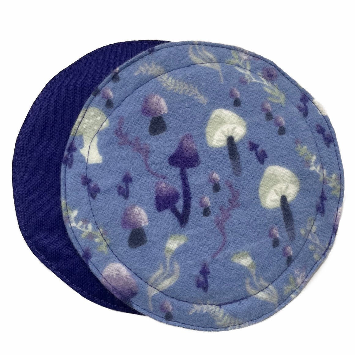 Two reusable breast pads against a white background. The pad on top is made from light blue cotton flannel with purple and grey mushrooms. The pad on the bottom is made from purple PUL fabric.