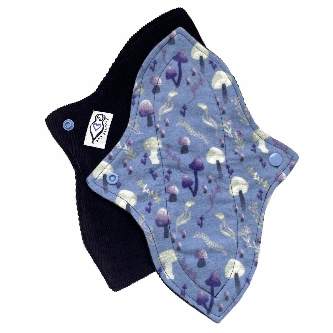 Two reusable menstrual pads with a contoured shape against a white background. The pad on top is made from blue cotton flannel with purple and grey mushrooms. The pad on the bottom is made from dark purple cotton corduroy fabric and has a white "Scarlet Eve" label.