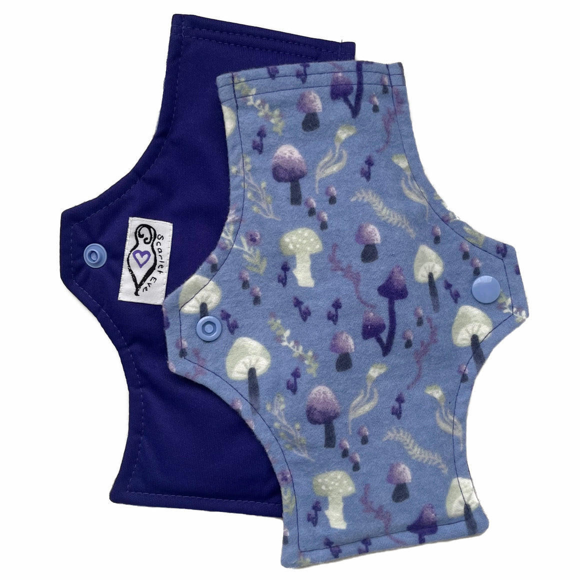 Two reusable menstrual pads with squared top and flared bottom shape against a white background. The pad on top is made from blue cotton flannel with purple and grey mushrooms. The pad on the bottom is made from purple PUL fabric and has a white "Scarlet Eve" label.