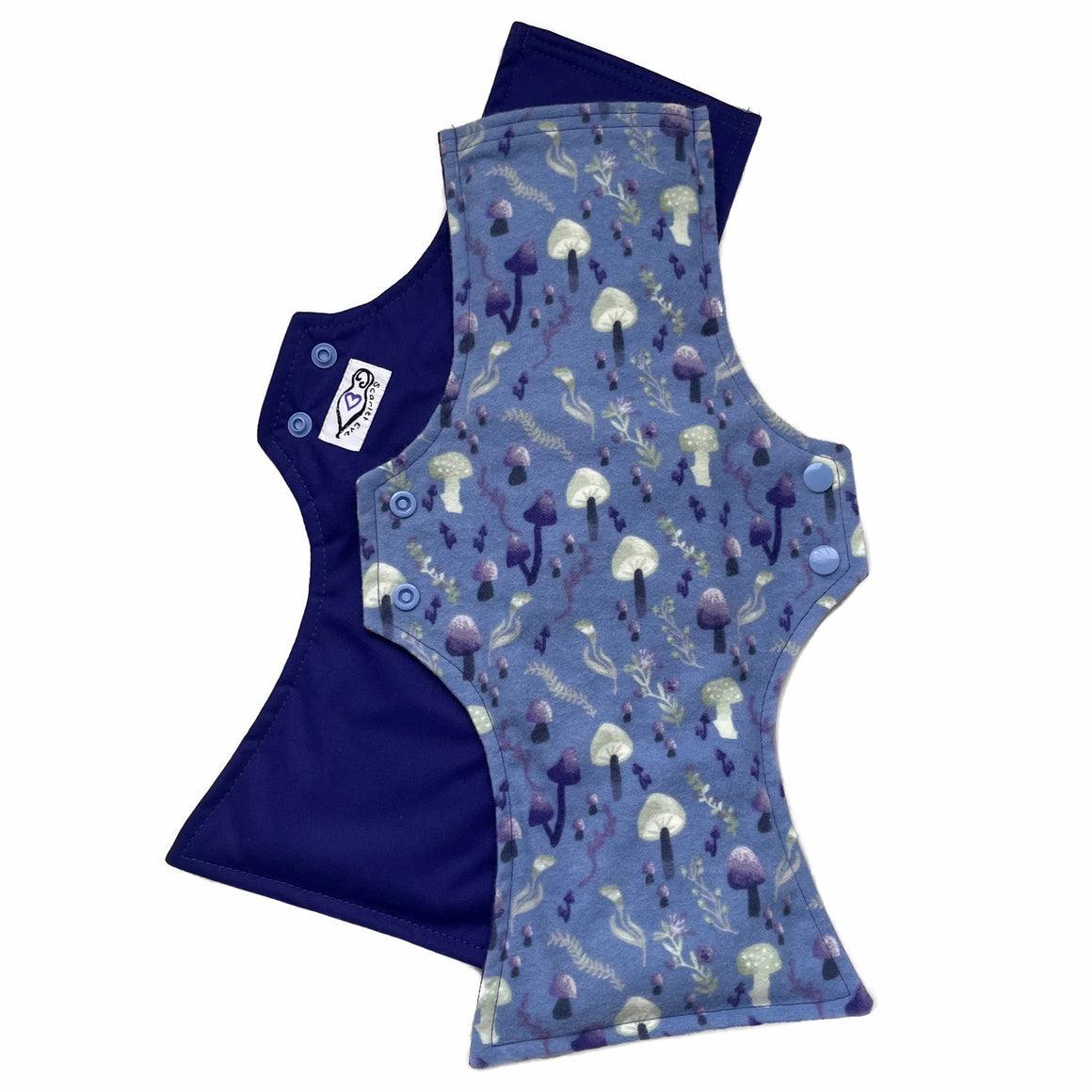 Two reusable menstrual pads with squared top and flared bottom shape against a white background. The pad on top is made from blue cotton flannel with purple and grey mushrooms. The pad on the bottom is made from purple PUL fabric and has a white "Scarlet Eve" label.