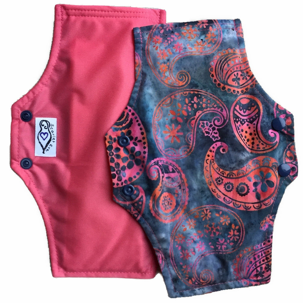 Scarlet Eve Candy Paisley Regular Pad. Top: Batik woven cotton with candy pink and orange paisley on a denim blue background. Back: Solid Candy Pink PUL. 3 layer flip out bamboo fleece booster. The absolute workhorse of the Scarlet Eve range.