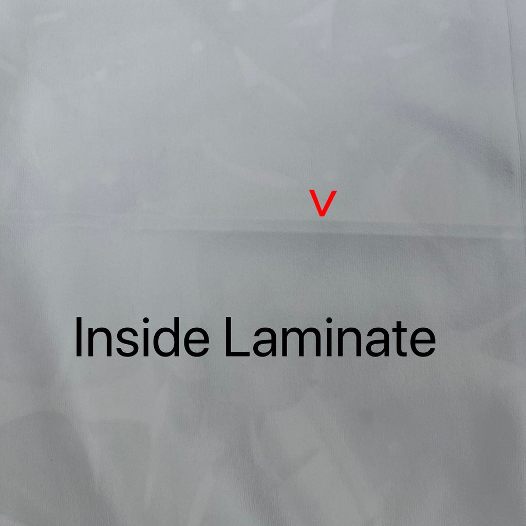 White fabric with feint large leaves showing through from the other side. A red arrow points to a fault line running across the fabric. Black text reads "Inside Laminate".