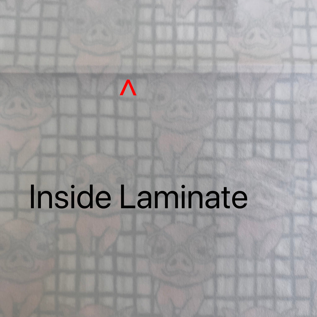 White fabric with feint black crosshatch pattern and cute pink pigs wearing glasses showing through from the other side. A red arrow points to a fault line running across the fabric. Black text reads "Inside Laminate".