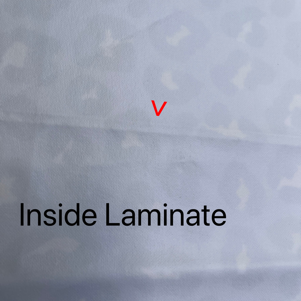 White fabric with feint leopard print showing through from the other side. A red arrow points to a fault line running across the fabric. Black text reads "Inside Laminate".