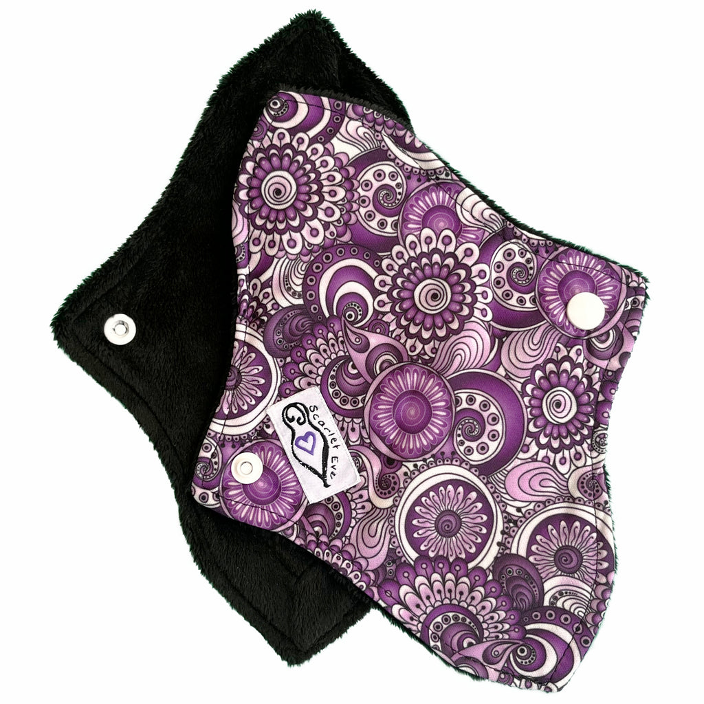 Scarlet Eve Purple Floral Curvy Mini Pad. Top: Plush Black Minky. Bottom: Purple, Black and White Floral PUL. 2 layer bamboo fleece booster sewn in. Contoured shape for snug, form-fitting comfort and coverage without bulk.