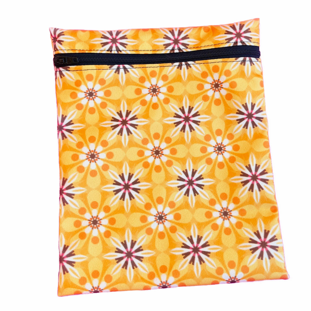 A rectangular zippered pouch against a white background. The wet bag is made from printed PUL fabric with a geometric floral print on dark yellow. A black coloured zip runs along the pouch towards the top.