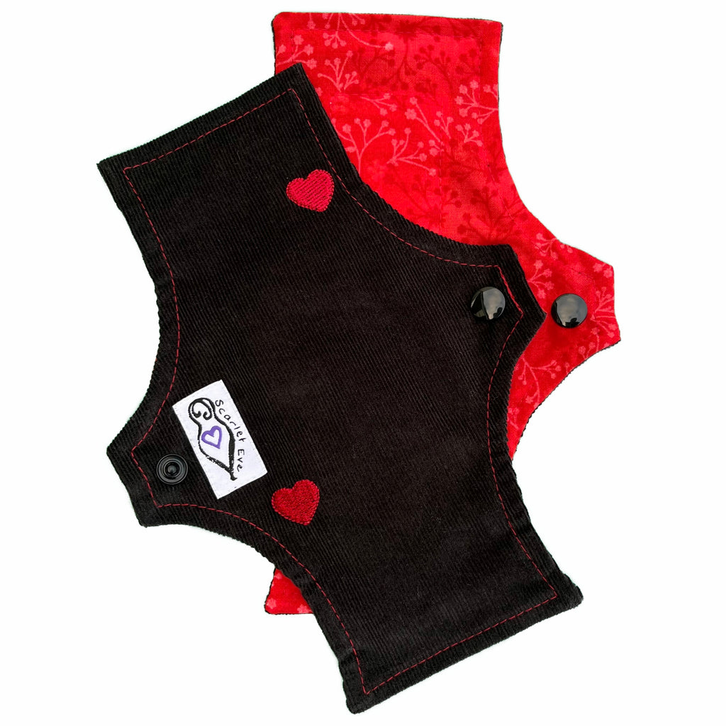 Scarlet Eve Scarlet Hearts Tiny Pad. Top: Scarlet Red floral woven cotton. Bottom: Embroidered Red Hearts on black cotton corduroy. Sewn in booster: Hemp Bamboo Fleece. Tiny Pads are ultra thin liners that meld to your underwear and become undetectable.