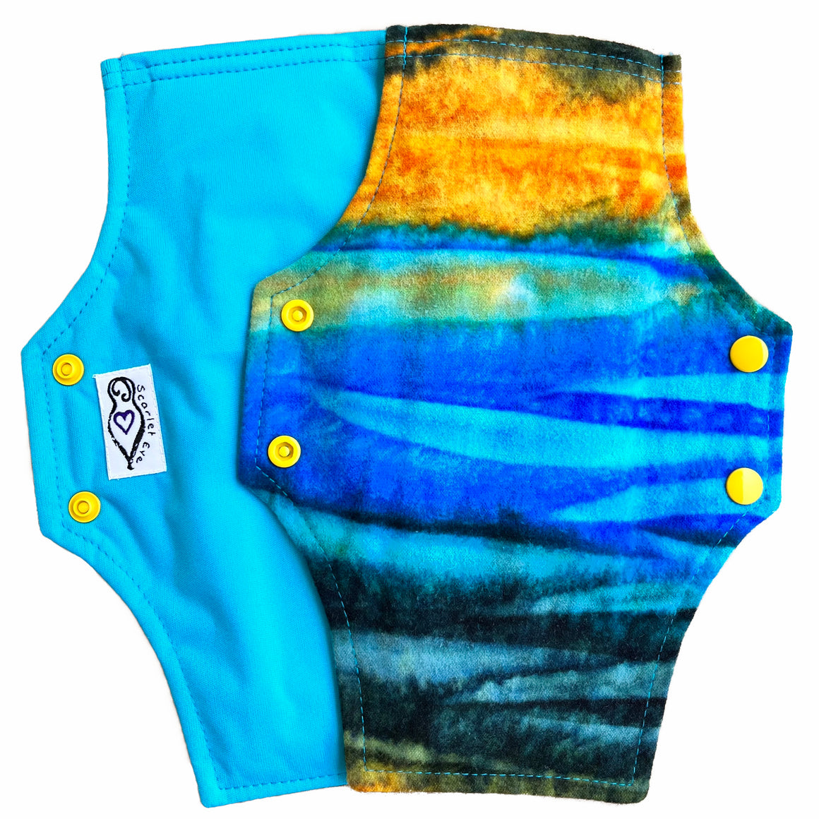 Two reusable menstrual pads with squared top and flared bottom shape against a white background. The pad on top is made from flannel fabric with batik striations of yellow, aqua and indigo. The pad on the bottom is made from aqua blue PUL fabric.