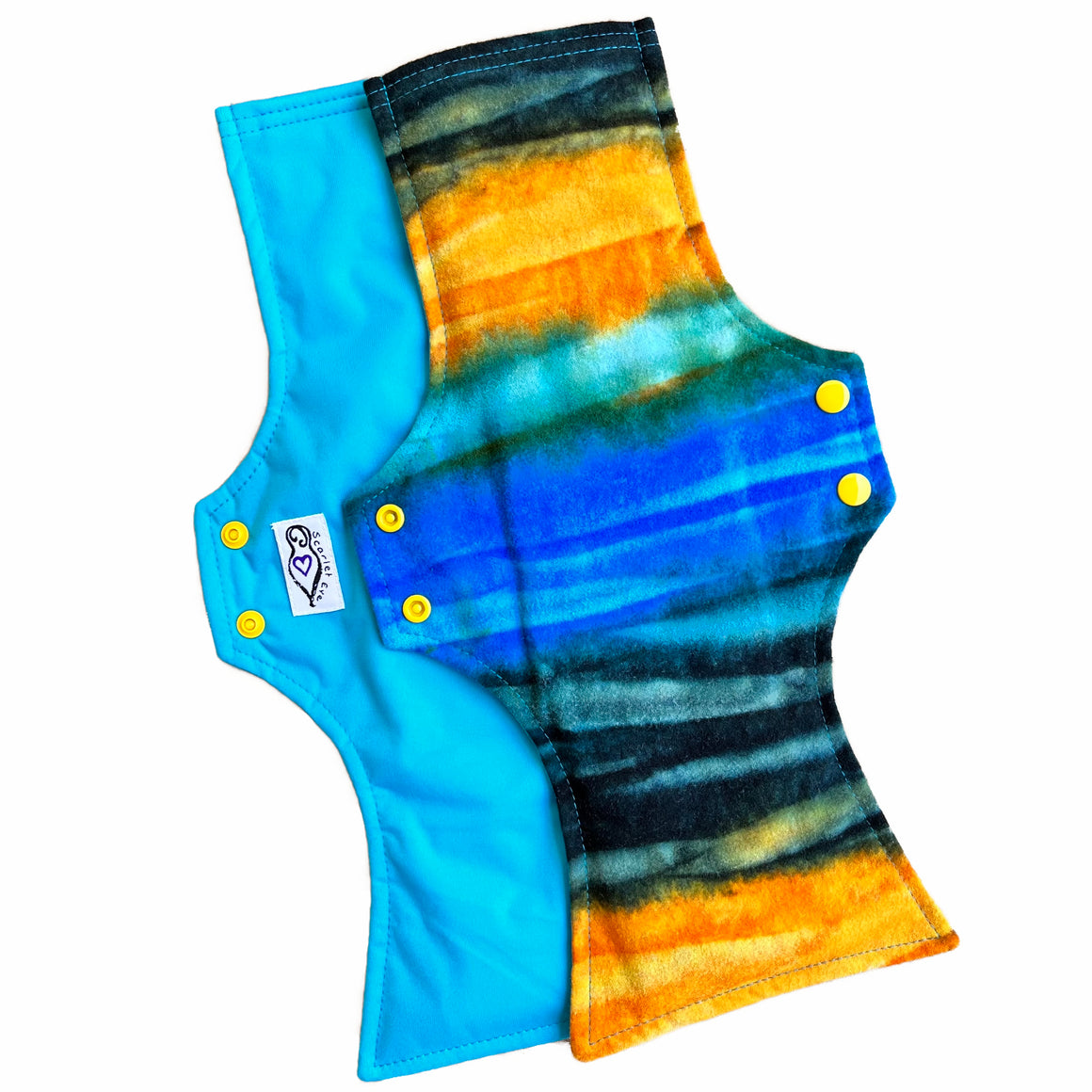 Two reusable menstrual pads with squared top and flared bottom shape against a white background. The pad on top is made from flannel fabric with batik striations of yellow, aqua and indigo. The pad on the bottom is made from aqua blue PUL fabric.