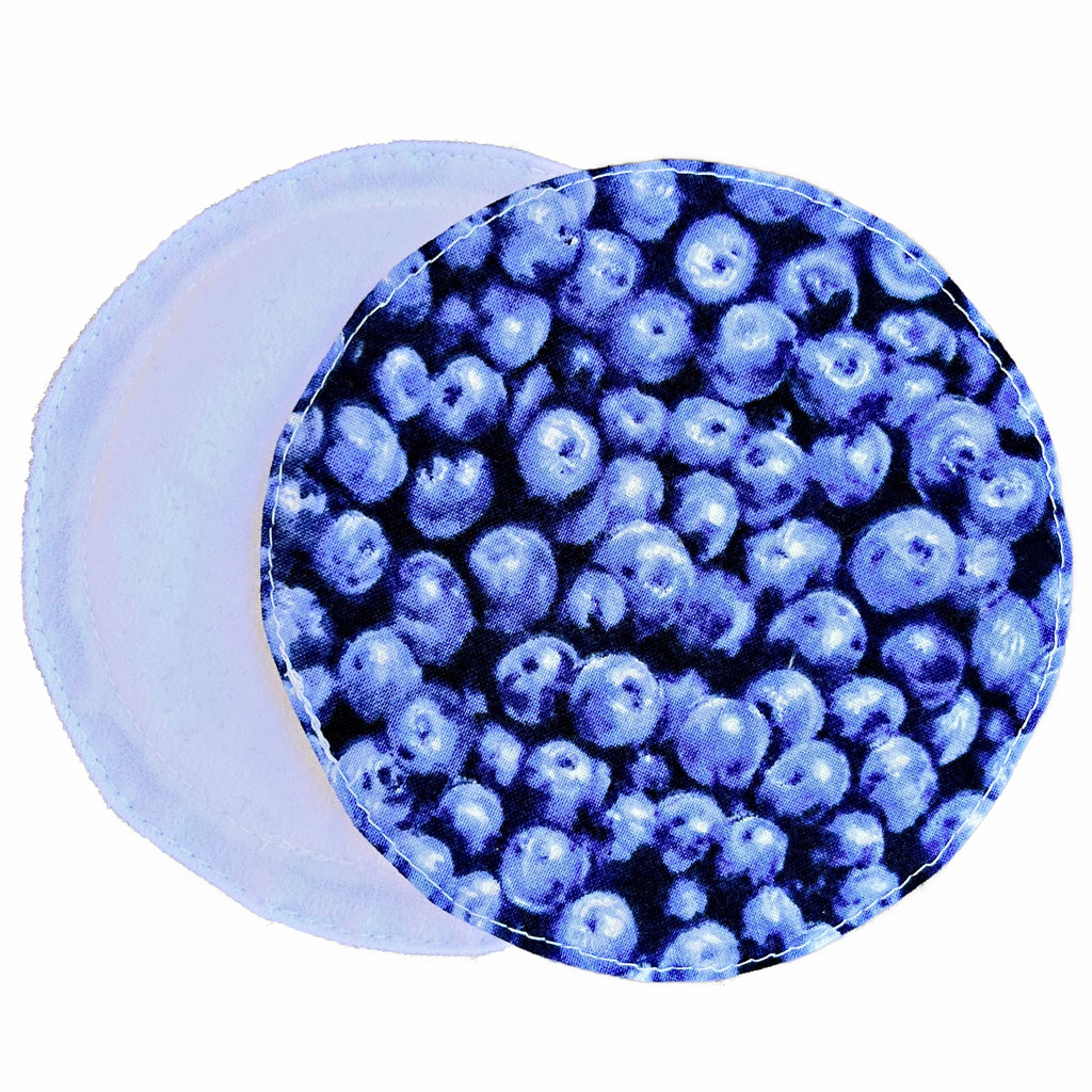 Two reusable nursing pads against a white background. The breast pad on top is made from PUL fabric with realistic blueberries print. The breast pad on the bottom is made from white suedecloth fabric.