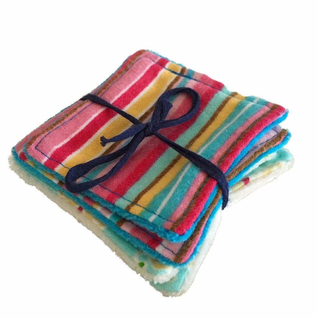 A set of 4 small square wipes, made from various flannel and velour fabrics, against a white background. The top wipe has a multicoloured stripe print. The wipes are laying flat and are tied with a navy blue bow.