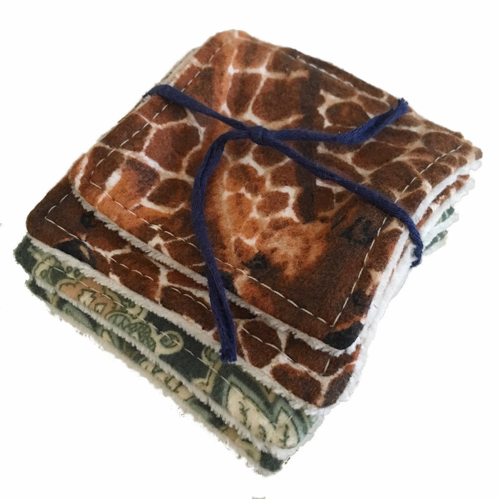 A set of 4 small square wipes, made from various flannel and velour fabrics, against a white background. The wipe on top has a giraffe print. The wipes are laying flat and are tied with a navy blue bow.