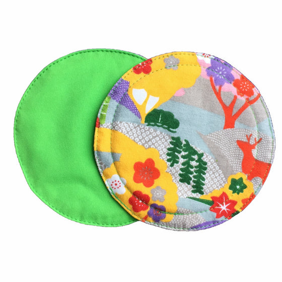 Two reusable nursing pads against a white background. The breast pad on top is made from cotton jersey fabric with a bright forest print. The breast pad on the bottom is made from lime PUL fabric.