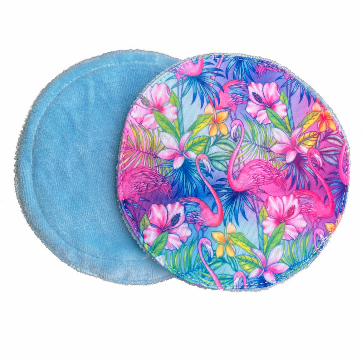 Two resusable nursing pads against a white background. The breast pad on top is made from light blue fabric with a bright, tropical flamingos print. The breast pad underneath is made from light blue bamboo velour fabric.