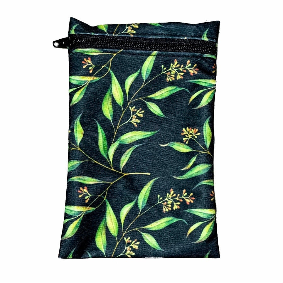 A rectangular zippered pouch against a white background. The wet bag is made from black PUL fabric with green leaves and yellow flower buds. A black coloured zip runs along the pouch towards the top.