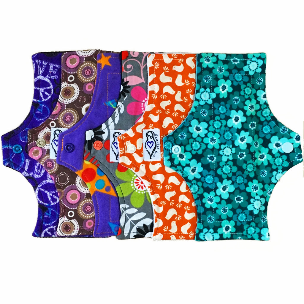 A set of six assorted panty liners with various colourful patterns, against a white background.  The reusable menstrual Pads are squared at the top and flared at the bottom.
