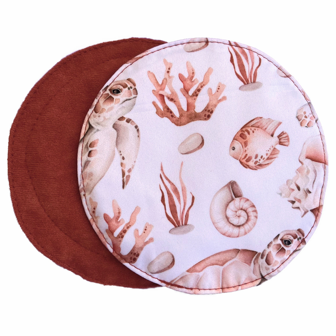 Two reusable nursing pads against a white background. The breast pad on top is made from white PUL with rust and cream sea creatures. The breast pad on the bottom is made from rust suedecloth fabric.