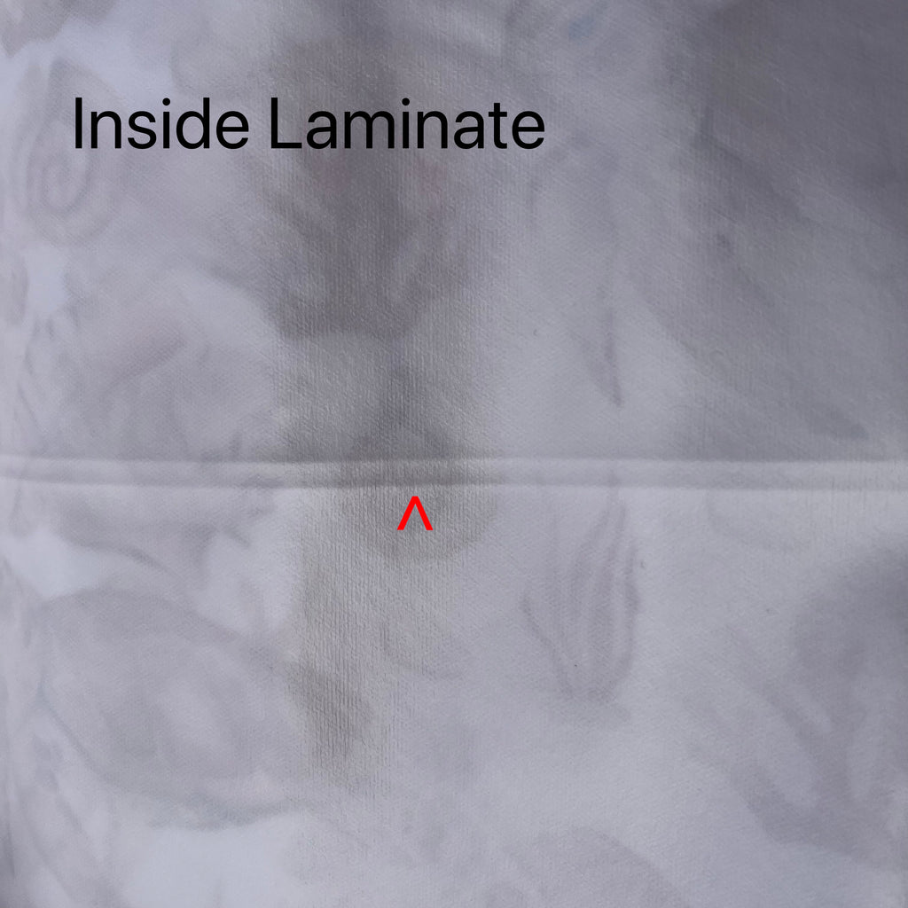 White fabric with feint sea creatures print showing through from the other side. A red arrow points to a fault line running across the fabric. Black text reads "Inside Laminate".