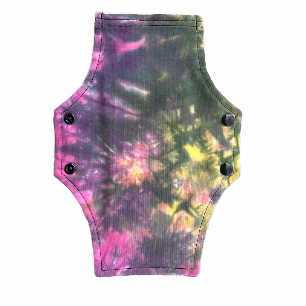A reusable cloth menstrual pad with a squared top and flared bottom shape, against a white background. The pad tie dye cotton lycra fabric in pastel pink, yellow and black shades.