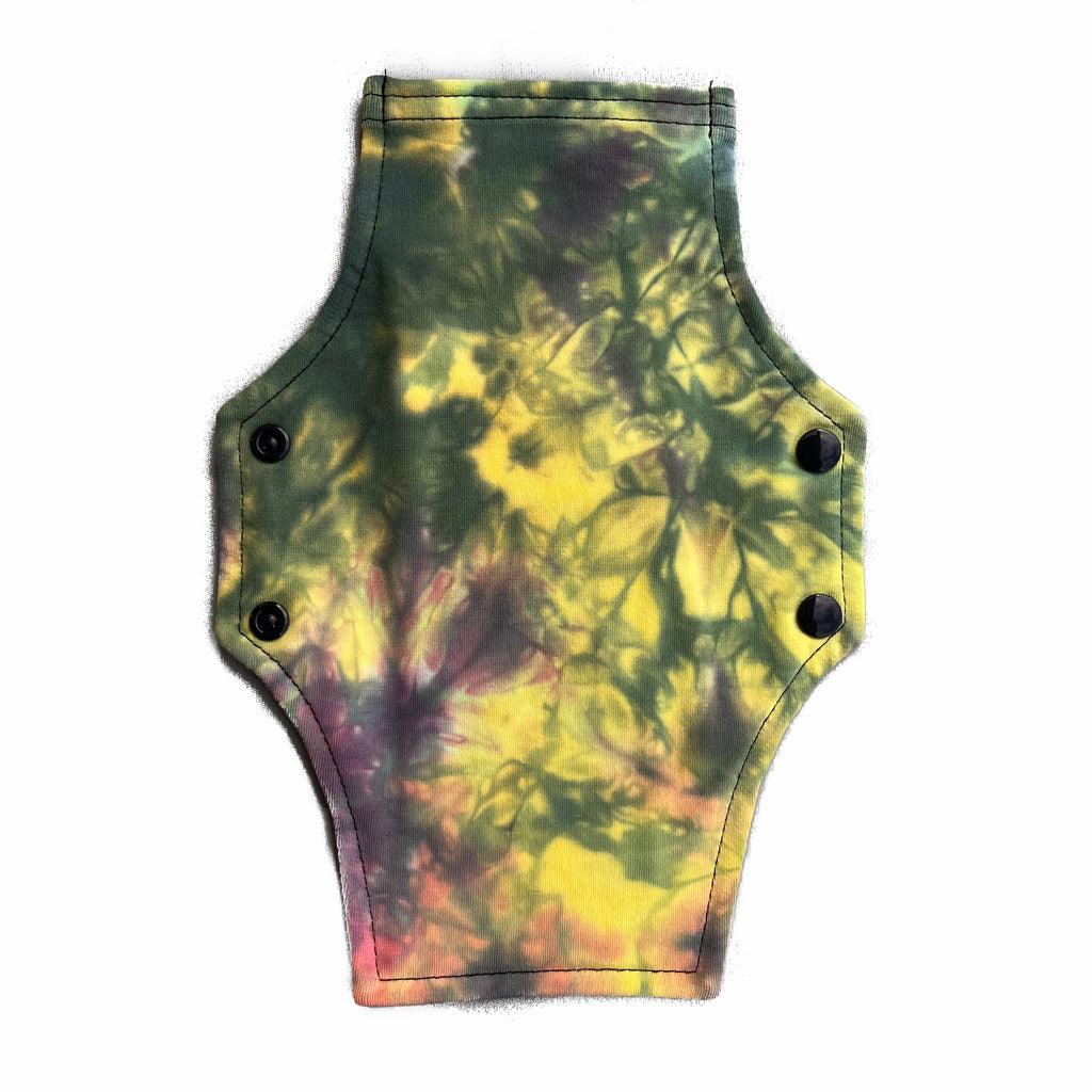 A reusable cloth menstrual pad with a squared top and flared bottom shape, against a white background. The pad tie dye cotton lycra fabric in pastel pink, yellow and black shades.