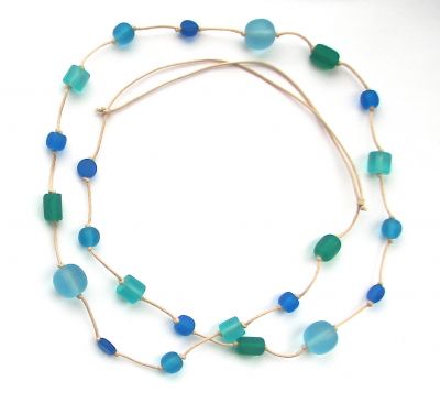 A long necklace in a circular shape against a white background. Blue and green beads are spaced along a light brown necklace thread.