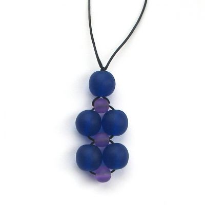 A necklace made from a cluster of blue and purple beads on black necklace thread, against a white background. 