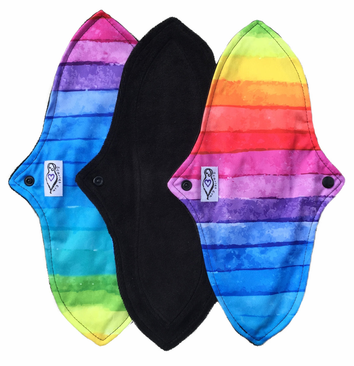 Three reusable menstrual pads with a contoured shape against a white background. The pads on each end are made from large watercolour stripes in various colours, and have a white "Scarlet Eve" label. The pad in the middle is made from black velour fabric. 