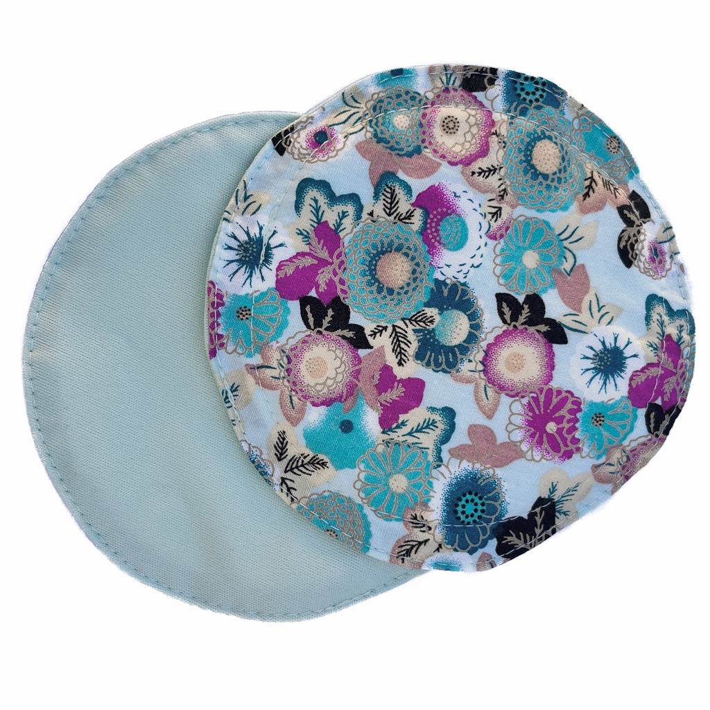 Scarlet Eve Sage Floral Breast Pads. Top: woven cotton with teal, hot pink, apricot, chocolate brown and cream flowers and leaves on a sage green background. Back: Solid Sage green PUL. 2 layers of bamboo fleece sewn in. Scarlet Eve breast pads have generous coverage and superior absorbency.