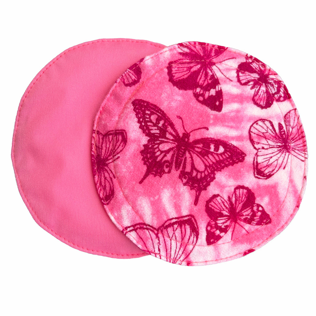 Two reusable nursing pads against a white background. The breast pad on top is made from light pink and white tie dye cotton flannel with maroon butterflies. The breast pad on the bottom is made from raspberry pink PUL fabric.