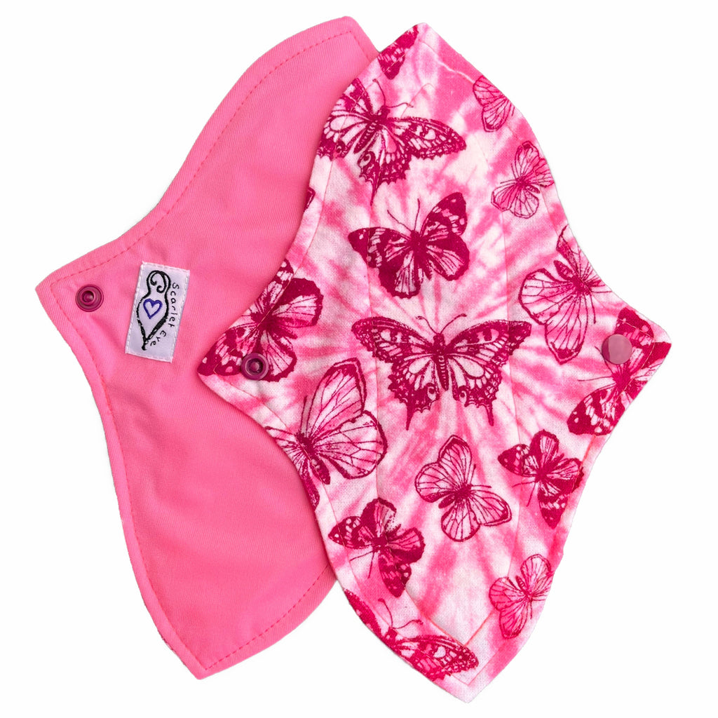Two reusable menstrual pads with a contoured shape against a white background. The pad on top is made from light pink and white tie dye cotton flannel with maroon butterflies. The pad on the bottom is made from raspberry pink PUL fabric and has a white "Scarlet Eve" label.