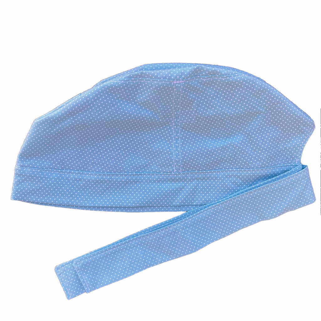 A blue and white scrub cap against a white background. The cap, bottom band and ties are made from light blue woven cotton with very small white dots.